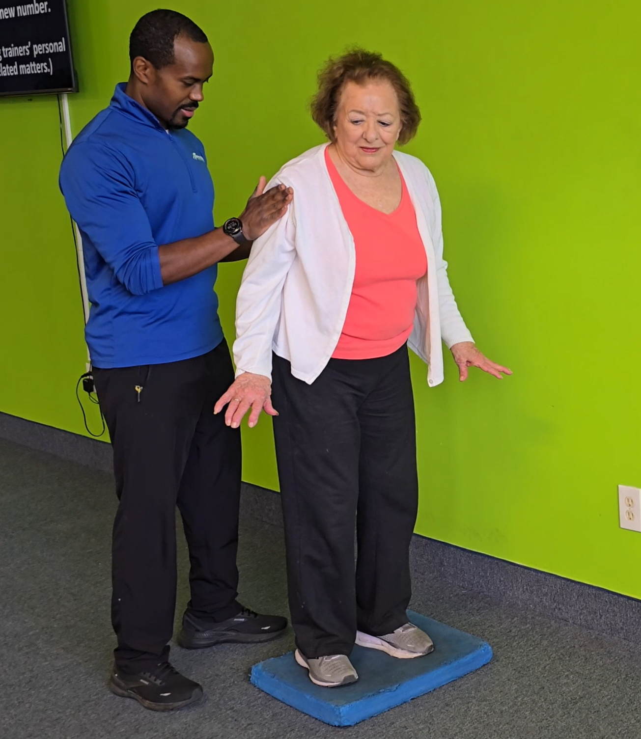 Trainer guiding an older adult through a balance exercise