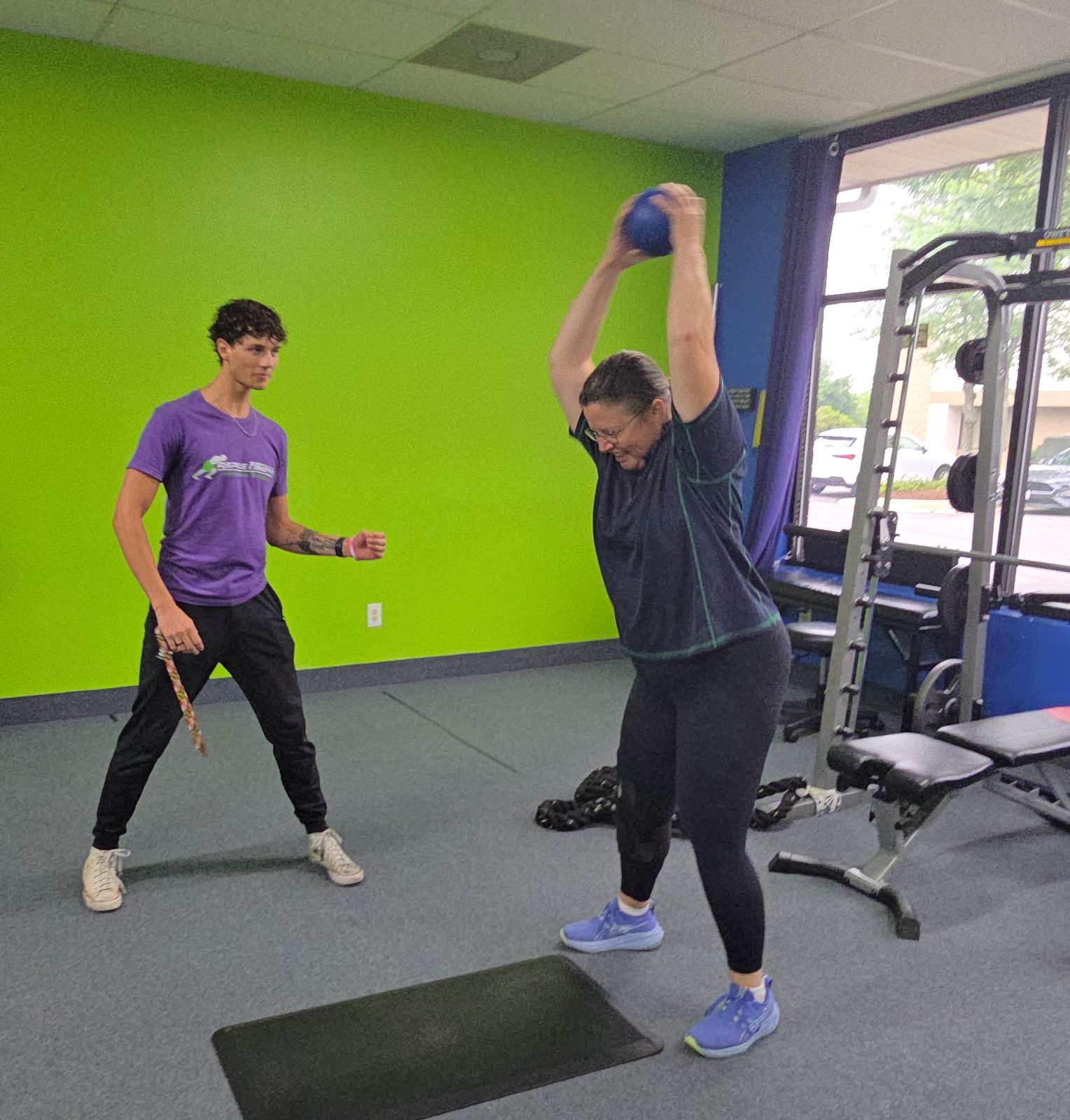 Repke Fitness trainer Noah coaching a client through a medicine ball slam